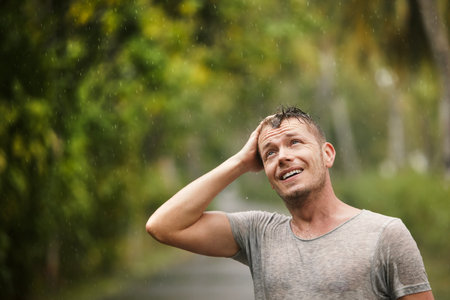 Portrait of man in wet clothes enjoying heavy rain in nature. Themes of life water, weather and environment.の写真素材