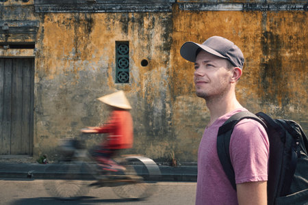Portrait of traveler with backpack. Man exploring streets of ancient city Hoi An in Vietnam.の写真素材