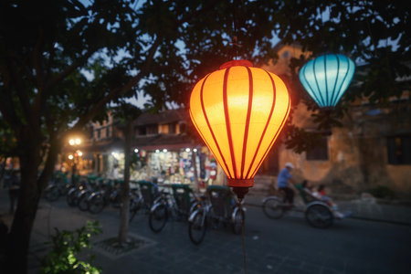 Traditional lanterns hanging on street in Hoi An in Vietnam. Evening life in ancient town with rickshaws and tourists.の写真素材
