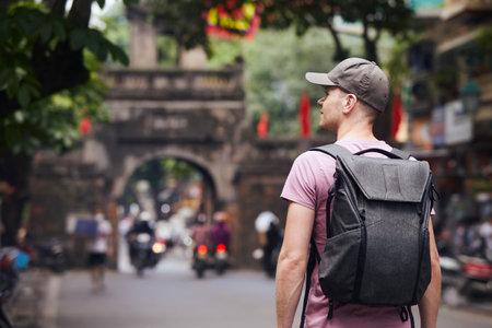 Traveler walking on busy asian street. Rear view of man with backpack in Old Quarter in Hanoi, Vietnam.の写真素材