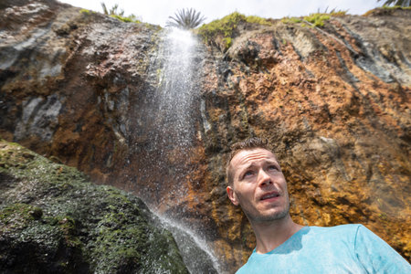 Portrait of man standing under waterfall in Tenerife, Canary Island, Spain.の写真素材