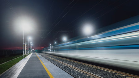Modern railway at night. Light trail of high speed train in railroad station. Moving modern...