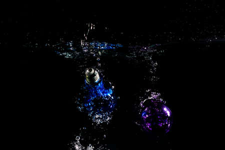 Colorful light bulb drops down the water.の写真素材