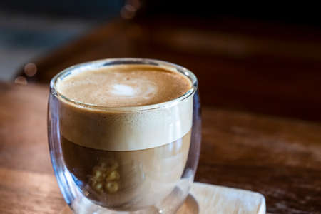 Cappuccino in a clear glass, rich color, beautifully served with crisp crackers.の写真素材