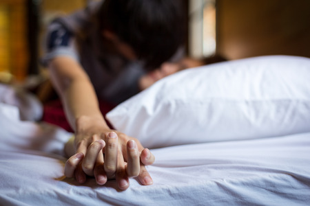 Romantic couple in bed enjoying sensual foreplay. Focus on hands man and woman.の写真素材