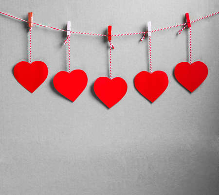 Red heart paper cut with natural cord and red clips hanging on the wall, copy space,valentines day -...