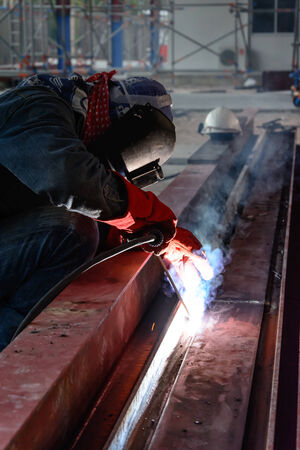 Welder with protective mask welding metal and sparks の写真素材
