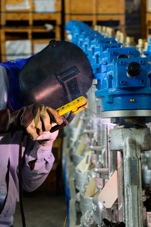 welder welding steel metal on valve