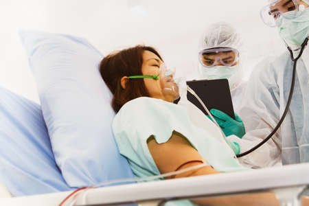 Asian woman with respiratory tract COVID-19 is lying in a bed, and the patient has been treated and cared for by the medical team in the hospital.の写真素材
