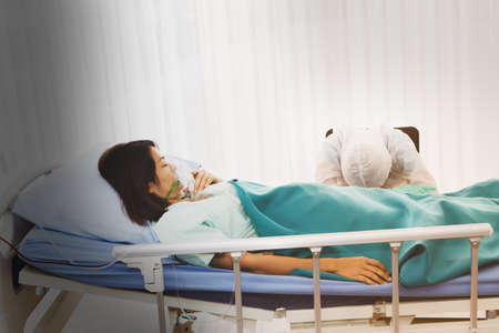 Female doctor responsible for caring for patients with serious influenza, fatigue, naps beside patients after hard work, caring for female patients for 24 hours.の写真素材