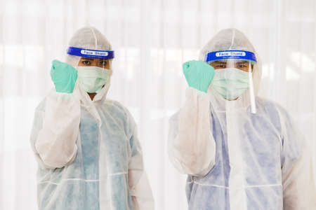 Male and female doctors wearing a face mask shield and protective clothing prepared to enter the screening area for coronavirus covid patients and people infectedの写真素材