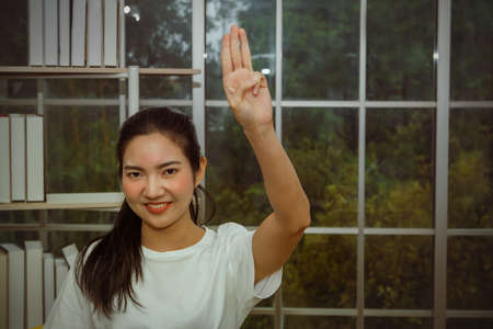Thai woman shows up a political three-finger symbol of expression for her home democracy.の写真素材