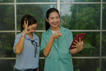 Two female teachers use sign language to communicate video-call conferences through their laptop online to understand their students.の写真素材