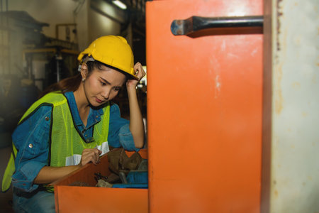 Concept factory mechanic work : Female industrial worker opened a large drawer of a tool cabinet, but felt frustrated, and forgot a shelf that couldn't find tools.の写真素材