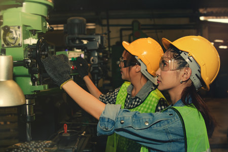 Teamwork two female technicians work together to inspect and control metal drilling machines for safety, check readiness of industrial plants, engine parts.の写真素材