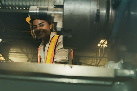 Beautiful female African american technician, engineering department, operate lathe with a happy work and safety professional in the industry.の写真素材