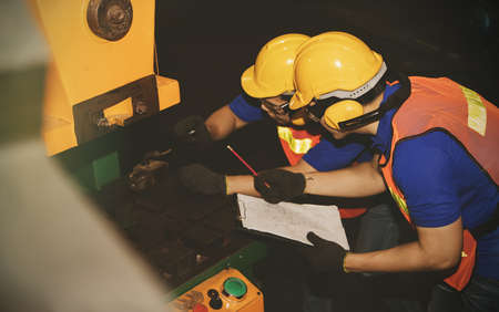 Monthly inspection of safety equipment : Engineering workers, engineers, technicians work as a team work, inspecting the use of hydraulic machinery in industrial plants for safety and efficiency.の写真素材
