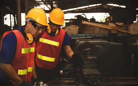 Teamwork and division of duties of professional metal factory technicians working on precision metal turning machines and put on protective equipment for safetyの写真素材
