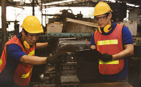 Teamwork concept : Together teamwork and the division of duties of professional metal factory technicians, work on metal lathes efficiently to ensure quality work.の写真素材