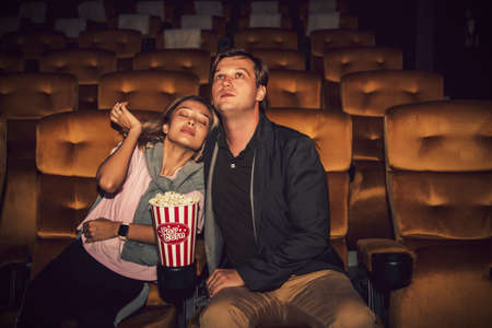 Couples, romantic at the cinema : The handsome man sat watching the movie with more interest than the beautiful girlfriend who sat asleep on the side.の写真素材