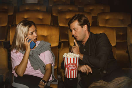 Young women talking on the phone interfering with watching movies of men sitting close to each other,this man had admonished, for her lack of etiquette, to stop speaking.の写真素材