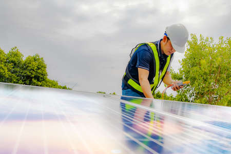 Electrical engineers work using a multimeter to inspect the new solar panel system on the roof of an industrial factory.の写真素材