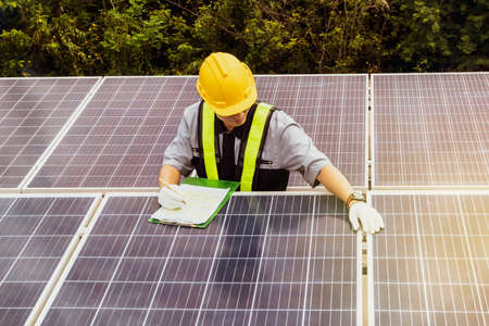 Male engineering technician workers wearing safety clothing work to record each solar panel during installation in order to test the power and to collect operational data: Selective Focusの写真素材