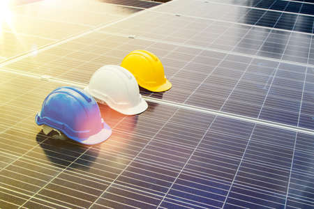 Concept safe operation : White, blue and yellow safety helmets for engineers, architects and workers on solar panels, solar power generation, renewable energy and industrial ecology.の写真素材