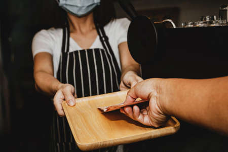 Hand close up female baristas who wear masks in food and beverage restaurants, provide cashless payments without contactの写真素材
