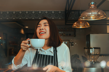 Female barista holds a coffee cup who seasoned herself with a passion for delicious coffee  enjoys having self-brewed coffee.の写真素材