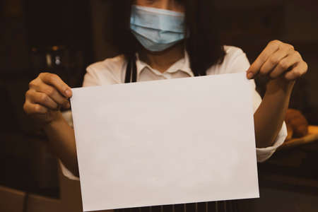 Business woman wearing a mask hand holding documents A4 I am busy with stress and anxiety due to an epidemic : A4 size document with copy space.の写真素材