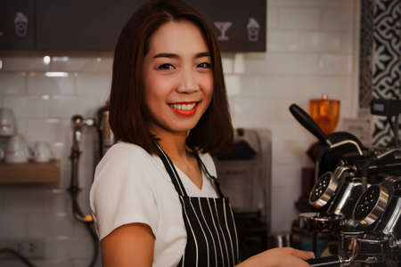 Female barista in a small business restaurant and beverage, she works with happiness and a smile with customer service.の写真素材