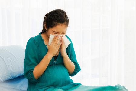 Pregnant women, unhealthy, causing complications of the common cold, and having allergies, sneezing on the patient's bed, using tissue to blow the fluid out of the nose for hospitalization.の写真素材