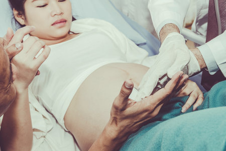 Caring for a pregnant woman by an expert pediatrician is examining the development of a baby in the stomach, with her husband having expectations and being close.の写真素材