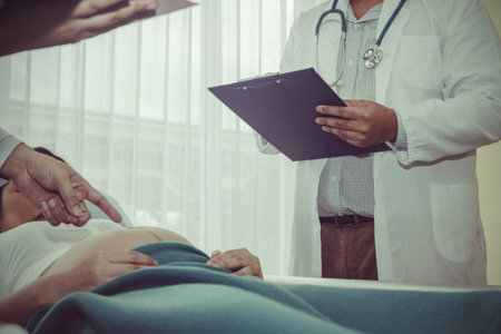 The male doctor recorded a report of a pregnant woman near birth, with a medical assistant diagnosing the pregnancy, strength and abnormalities of the fetusの写真素材