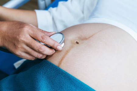 Doctors use medical headsets to listen to the fetus and develop infant movements in the mother's prenatal tummy, taking care during antenatal care.の写真素材