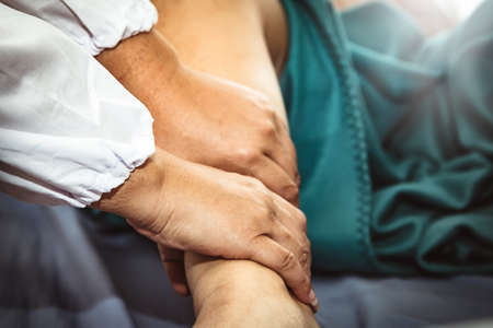 The female doctor takes care of the pain in the sore muscles and the legs of the pregnant woman due to the weight gain of the baby. In each month, the doctor uses a gentle massage hand to relax.の写真素材