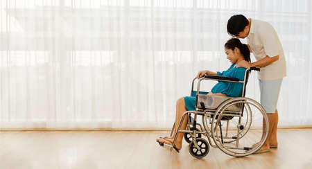 Happy family : Husband and wife take care of health, pregnant wife ride in a wheelchair for antenatal care, childbirth, see an obstetrician and gynecologist in the hospital : Copy spaceの写真素材