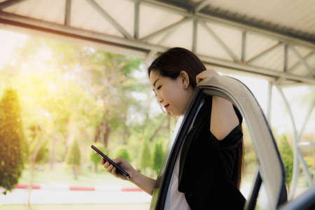 Concept of everyday life, the online social world : Beautiful woman uses a smartphone anywhere, even her free time, always using the phone even in the parking lot : Copy spaceの写真素材