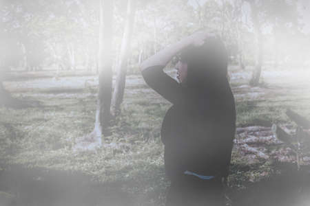Girl wandered in the winter forest. The image in the foreground was dense fog in the forest, and there were trees in the way. Causing her to travel without a destination with stressの写真素材
