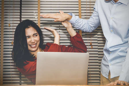 Concept harassment of women in the office : Beautiful woman secretary was harassed by a man, a boss in the office, and she showed a rubbish face using her hand to prevent fear harassment.の写真素材