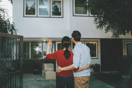 Rear view couple sadly bid farewell to their old house and misses their back because they had to move to their new home because of financial debt.の写真素材