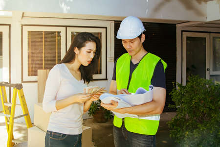 Architect offers a home improvement blueprint to the woman whose homeowner looks at the floor plan and is assessing the monetary costs for renovating and decorating this old home : Selective Focusの写真素材