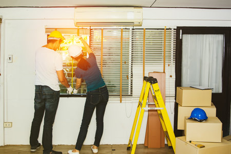 Couple, husband and wife measure the size of the old louvered windows and renovate the house to modernize it : Families work together happily and wear safety equipment.の写真素材