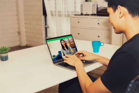 Concept of a new normal life : Video calls between lovers, chat on cameras, home tablet PC, greetings of men and lovers towards women lovers : Back view Couple happy to talk.の写真素材