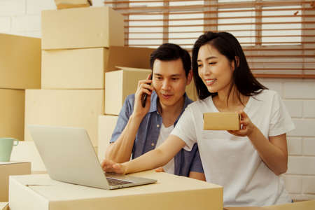 Asian couples doing SMEs deliver their products online to customers who order products via the Internet, helping to sell happily : Work From Home online : Selective Focusの写真素材