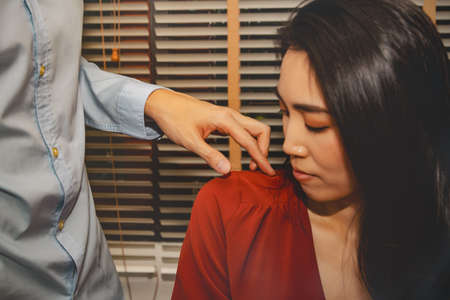 Concept harassment of women in the office : Unwanted man's hand Negative behavior, abuse of liberty, fingers touching beautiful woman's shoulder while working in office roomの写真素材