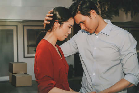 Concept house sales and relocation : Couple consoling together in front of the house in grief and sorrow because they want to sell their home and move away from their original home.の写真素材