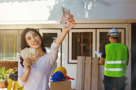 Home Renovation Concept : Pretty Asian women enjoy having the cash they have accumulated to renovate and decorate an old white house. with a male architect responsible for the design projectの写真素材