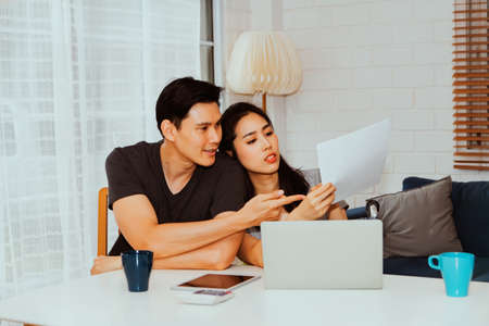 Young couple working at home : Couples look at white paperwork and analyze and solve problems.の写真素材